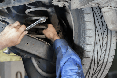 hands holding a wrench behind a car tire