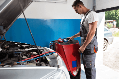 mechanic in overalls checking the battery health of a car with open hood